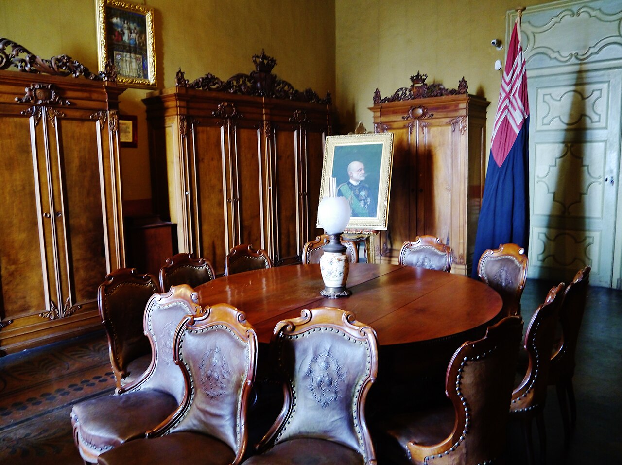 A corner room with period furniture and royal portraits